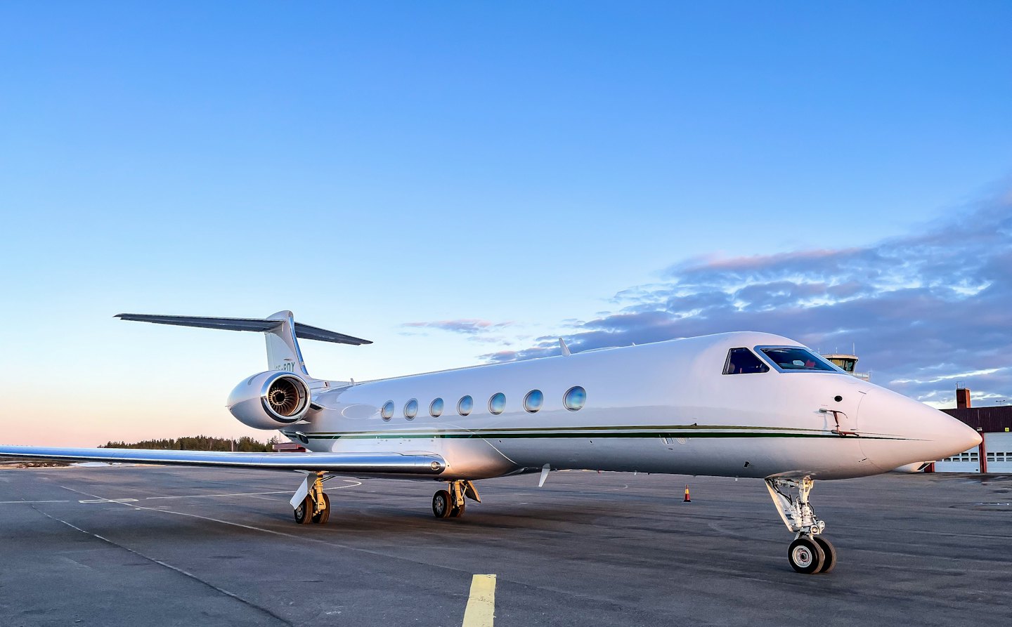 Een witte privéjet geparkeerd op de luchthaven-tarmac.