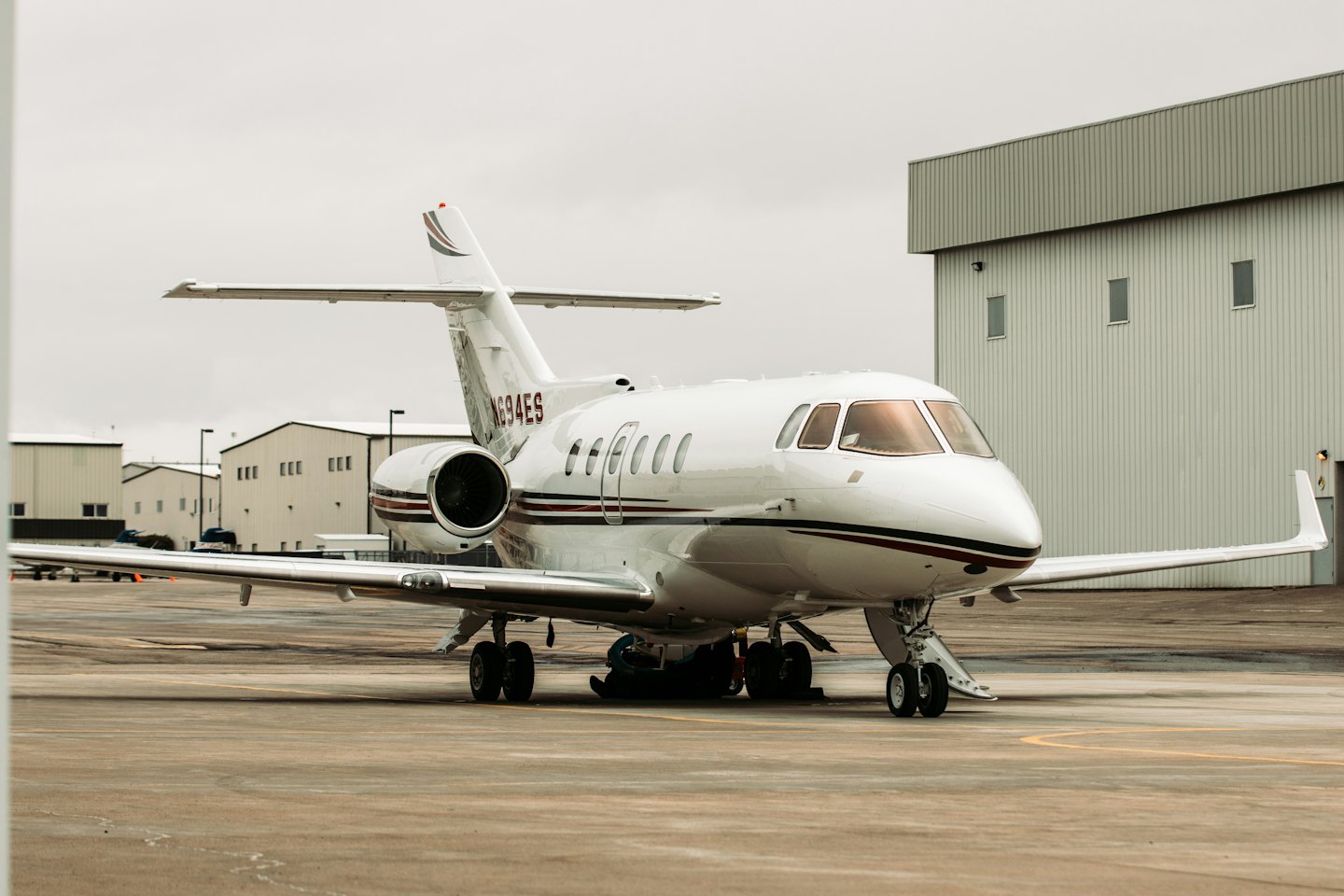 Witte privéjet met rode en zwarte strepen geparkeerd op het tarmac.